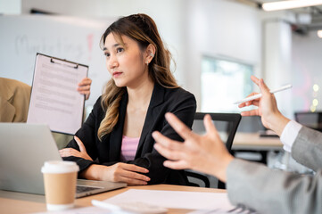 Asian businesswoman crossed arms and ignoring or unbothered by workplace dispute at office's table.