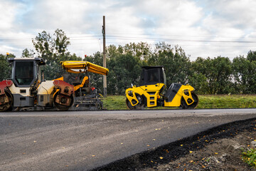 Asphalt rollers and paving machines working together on new road construction site