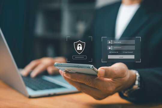 Businessman using smartphone and laptop with virtual login screen, cybersecurity protection, data privacy, secure access, and online password authentication technology.