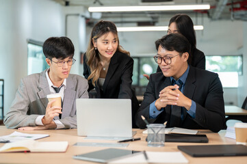 Businesswoman talking while male coworker looking at laptop on wooden table in office's meeting room
