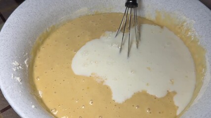Close-up of whisking eggs, sugar, and milk in a bowl — pancake batter preparation, perfect for culinary content, recipe videos, ingredient ads, and educational clips