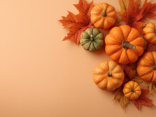 Background poster of pumpkins and autumn colored maple leaves isolated on a peach background with copy space for text. Suitable for halloween and autumn designs
