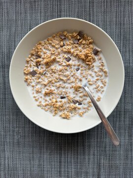 Crunchy muesli with chocolate chunks and milk in a bowl, healthy breakfast choice