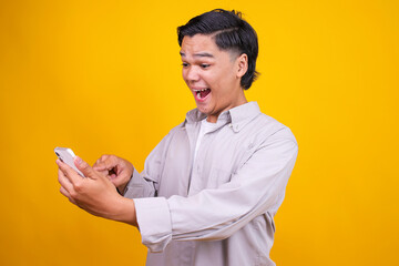 Young Asian Guy Reacts With Joyful Surprise While Looking At Smartphone