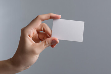 The hand holds a small white invitation card. Mockup business card