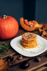 Delicious pumpkin pancakes with nuts, served on a plate. Autumn breakfast.