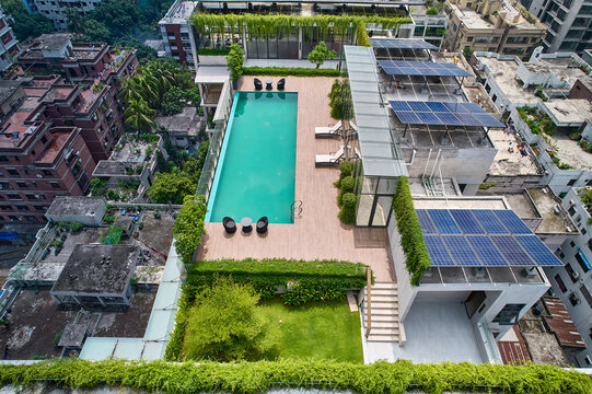 Aerial view of a rooftop swimming pool with lounge chairs, solar panels, and a modern deck overlooking the urban skyline. Ideal for architecture, luxury living, and contemporary outdoor design.
