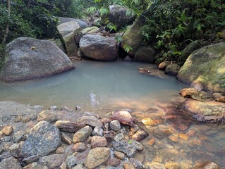 A pool of blue water surrounded by rocks in tropical jungle 