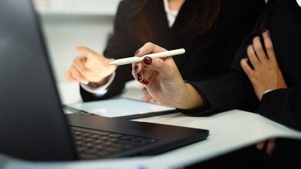 Close up of businesswomen collaborating on project using digital tablet at desk