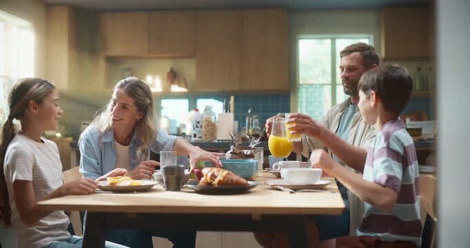 Family Enjoys a Healthy Lunch in a Sunlit Kitchen, Sharing Fresh Orange Juice and Croissants. Parents and Children Engage in Cheerful Conversation, Nutritious Meal Experience