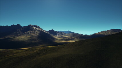 Breathtaking view of expansive mountain ranges illuminated by the early morning sun, creating deep shadows and highlighting the rugged terrain in serene tranquility.