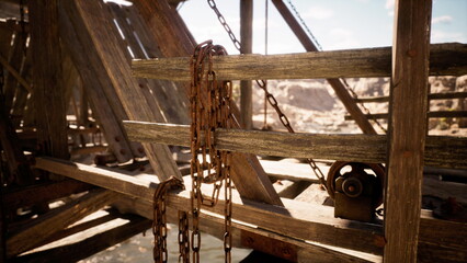 Old wooden beams support a structure under a bright sky. Rusted chains hang loosely, hinting at past use, while the rugged desert terrain stretches beyond.