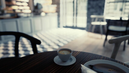 A cup of coffee rests on top of a wooden table in a modern cafe interior.