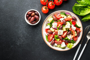 Greek salad in craft plate on black kitchen table.