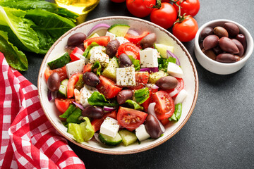 Greek salad in craft plate on black kitchen table.