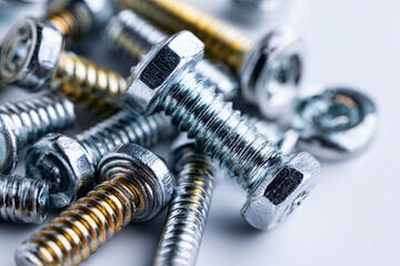 Metal screws and bolts gleaming against white background, randomly positioned, highlighting precision engineering and mechanical assembly potential