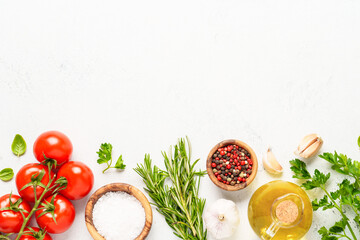Spices, herbs and vegetables with olive oil on white kitchen table.