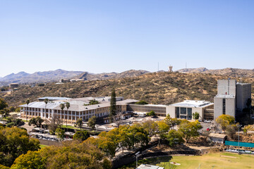 Naklejka premium Downtown Windhoek, Namibia, with tall contemporary buildings, wide streeodern ts, moving cars, and a clear blue sky.