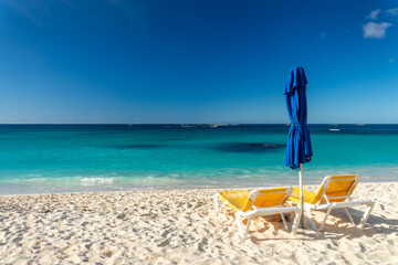 Two yellow beach chairs and blue parasol in Shoal Bay beach, Caribbean dream and landscape, Anguilla island, British West Indies