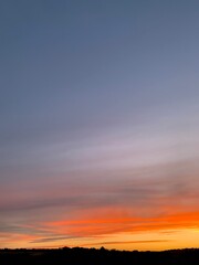 Fototapeta premium Beautiful colorful sunset sky with vibrant orange and purple clouds above dark forest silhouette