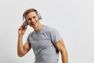 smiling young caucasian man wear grey t-shirt listen music on headphones hold hand on ear isolated on white background cyber security digital detox concept
