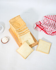 Loaf of white bread with slices on cutting board and red cloth