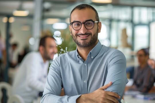 Confident Middle Eastern businessman leaning on desk in office accessories accessory glasses.