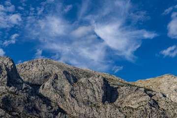 Fototapeta premium Gray rocks with small vegetation against the sky. Mountain landscape, Croatia. copy space