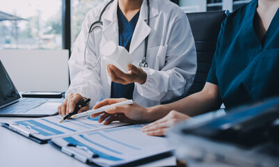 Medical team meeting analyzing blood test results in hospital laboratory. Doctors and scientists in lab coats are having a discussion about blood test result, holding test tubes and taking notes.