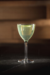 Elegant green cocktail with citrus garnish in vintage glass on black marble surface