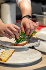 Male chef adds greens on bruschetta in restaurant kitchen
