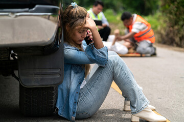 shocked woman driver hit person calling sitting at car. scared asian woman making phone call shaking in fear after crash victim. car accident scene on roadside with shocked woman sitting using phone