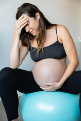 Pregnant woman experiencing discomfort while sitting on exercise ball