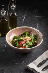 Fresh spinach salad with salmon, almonds and vegetables in ceramic bowl