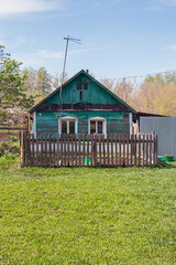 A small house with a green roof sits in a grassy field