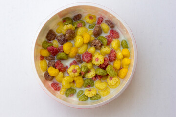 A bowl of colorful cereals with milk isolated on white background.