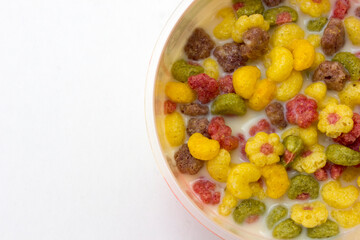 A bowl of colorful cereals with milk isolated on white background.