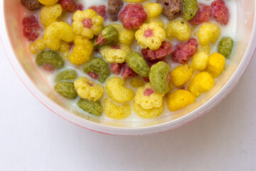 A bowl of colorful cereals with milk isolated on white background.