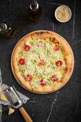 Caesar pizza with cherry tomatoes, lettuce and grated cheese on wooden board