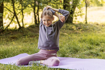 Preteen girl stretching arms during yoga outdoors