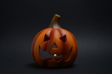 Carved jack-o-lantern pumpkin with candle inside, spooky face glowing faintly in dark background, symbol of Halloween festivity and eerie decor.
