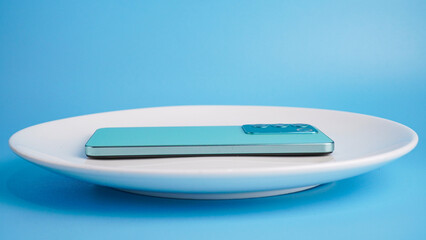 Smartphone on white plate with blue background