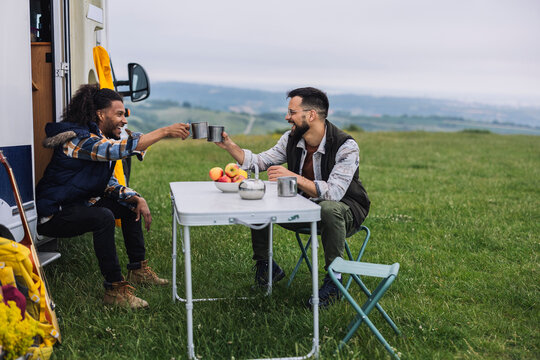 Friends toasting near camper van enjoying outdoor lifestyle