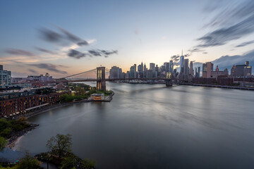Obraz premium Lower manhattan financial district with the Brooklyn bridge during sunset with long exposure smooth water