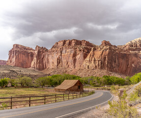 Curving road around a wooden shed with mountain back drop in Fruta, Capitol Reef, USA