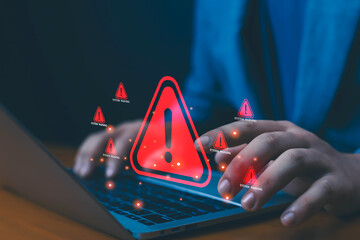 Person typing on laptop with red system warning alert icon, concept of cybersecurity threat, malware attack, data breach, computer virus, hacking risk, and information security protection.