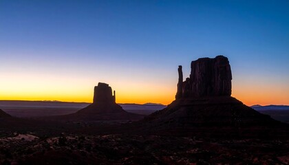 Monument Valley at sunrise with vibrant sky and silhouetted buttes.