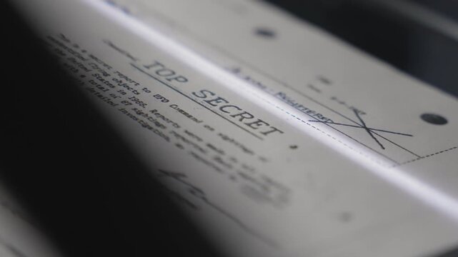Top secret report or document passing through scanner or copy machine in dark room. Close up on censored classified confidential government paper with intelligence sensitive information leaked exposed