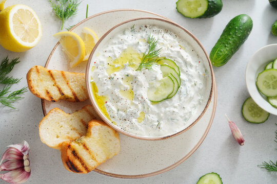 Tzatziki salad with roasted bread in white bowl on white background. Homemade Tzatziki salad with olive oil. Top view.