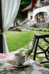 A cup of tea sits on a table overlooking a lush green garden.